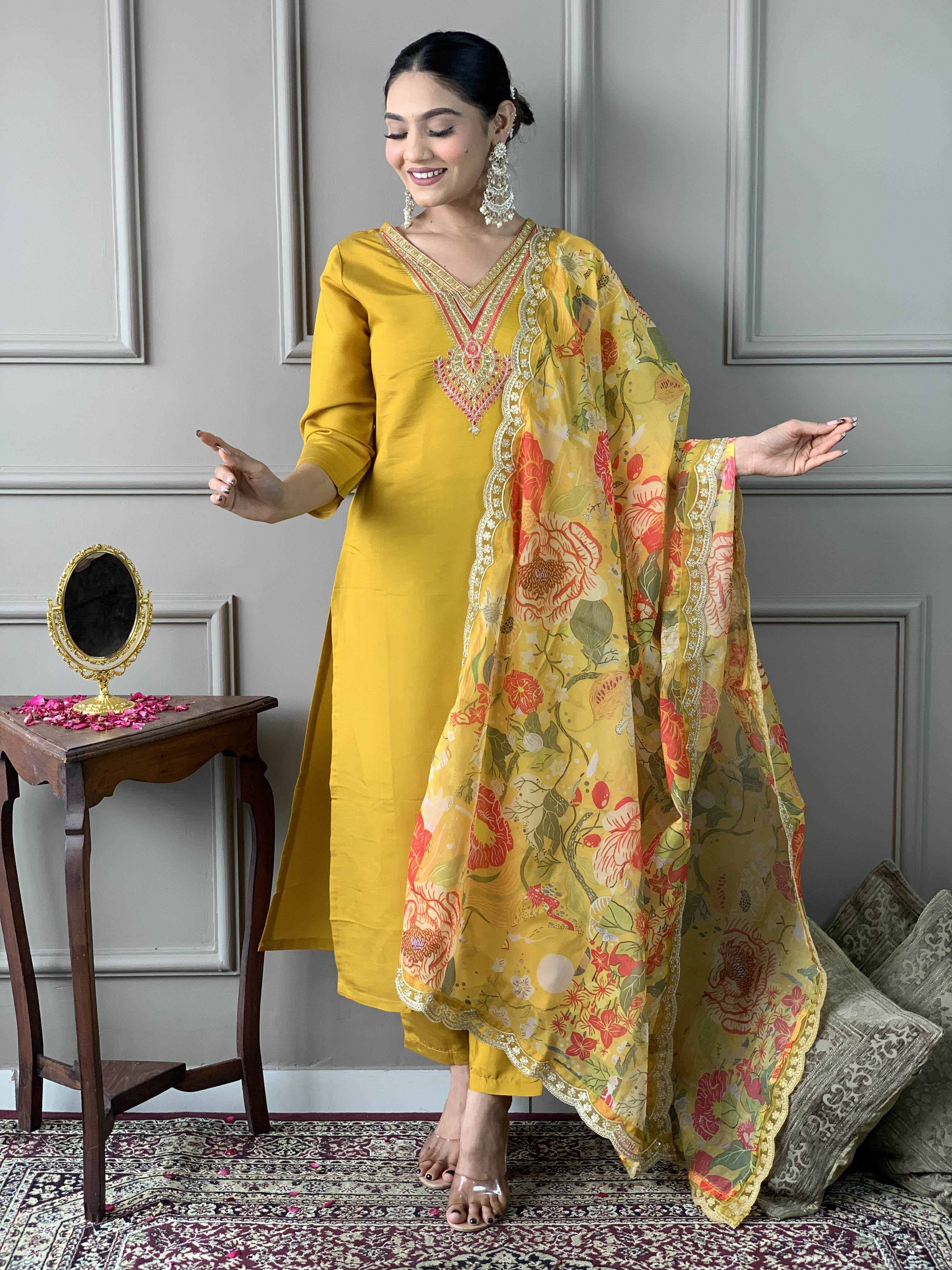 Woman in a yellow traditional outfit with a floral dupatta .