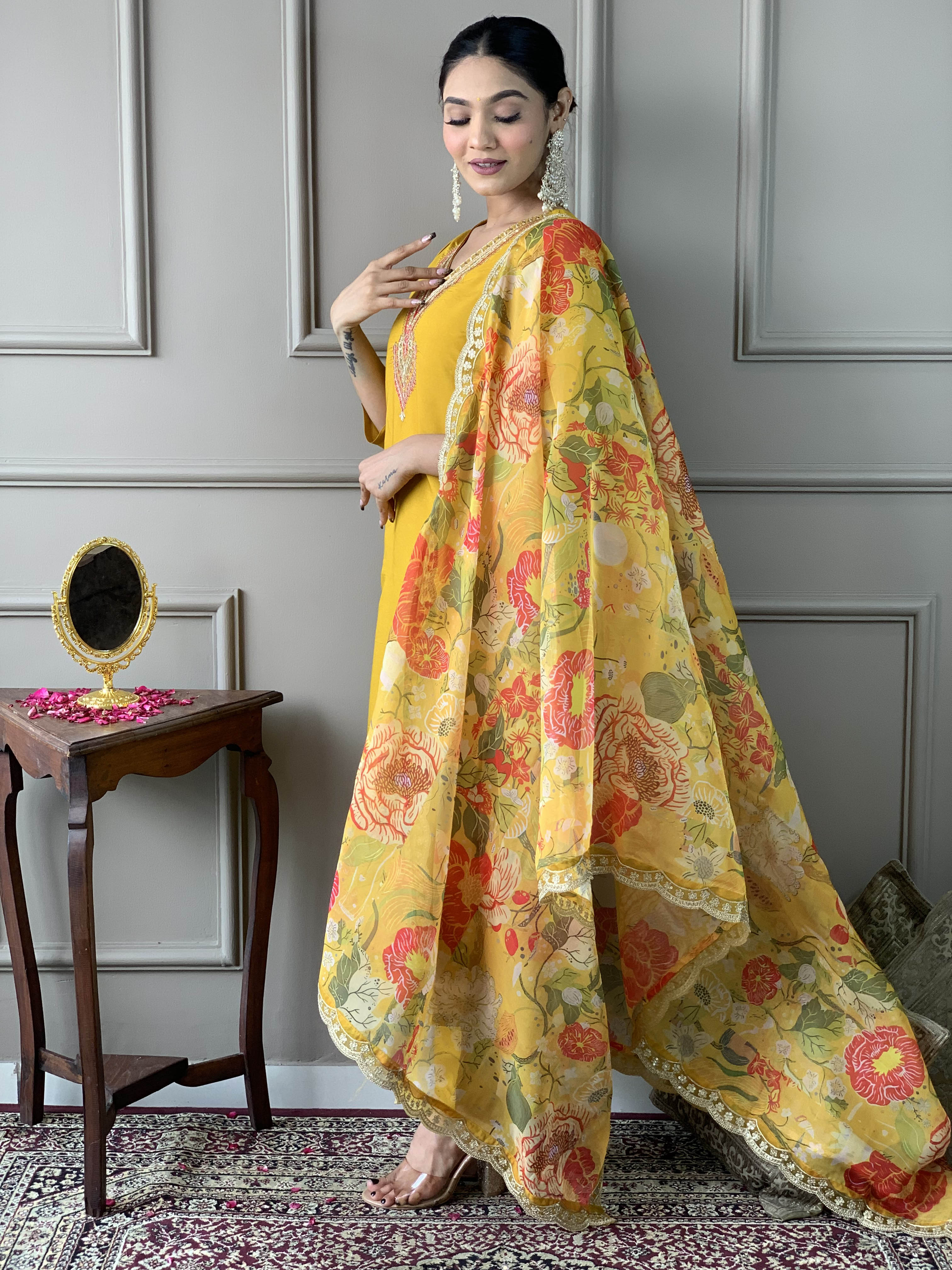Woman in a yellow traditional outfit with a floral dupatta .