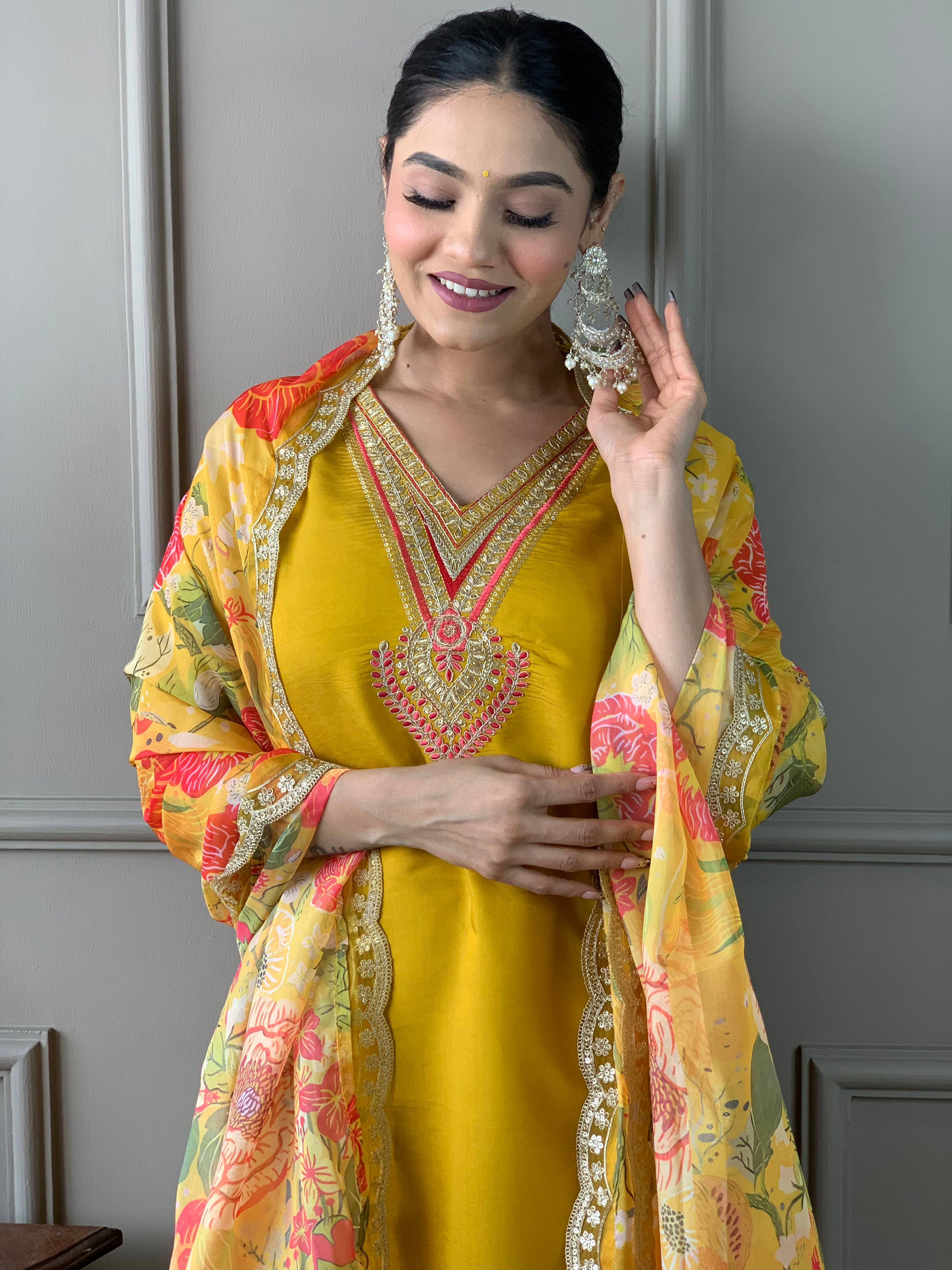 Woman in a yellow traditional outfit with a floral dupatta .