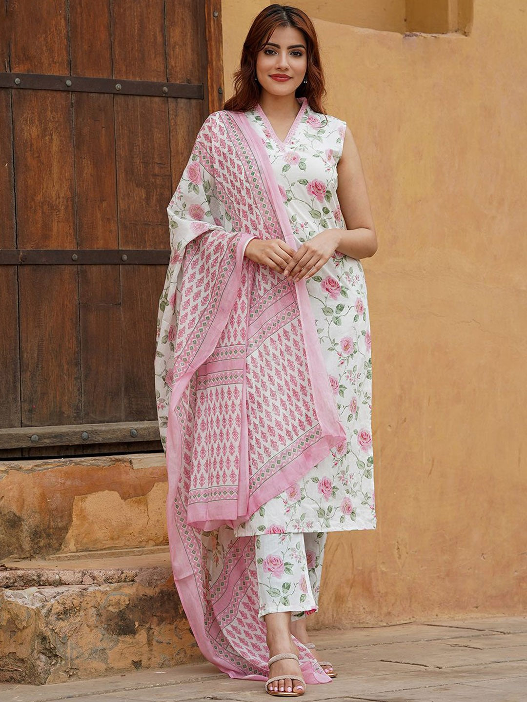 Woman wearing a floral outfit with a pink dupatta .