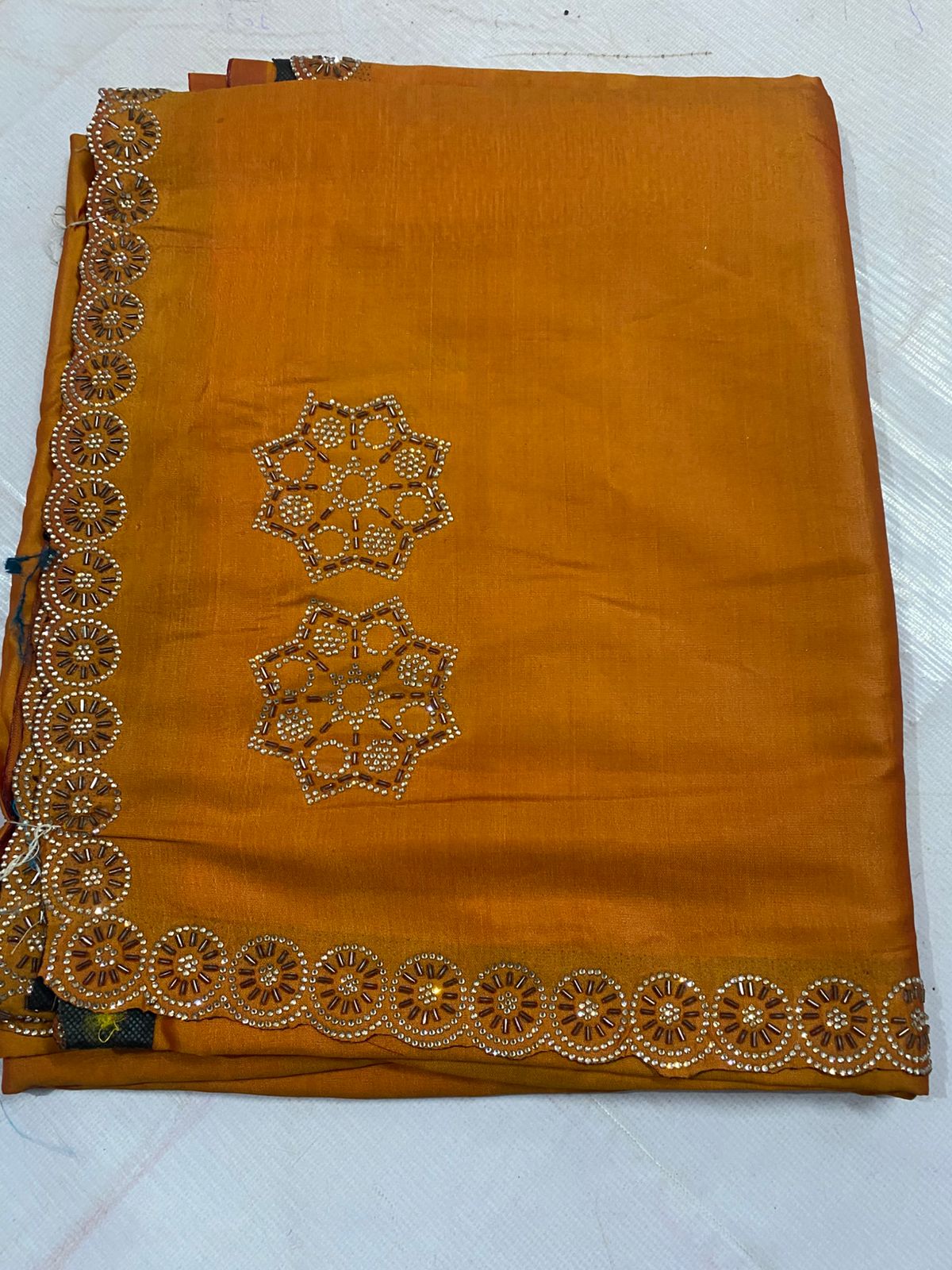 Yellow fabric with floral lace trim on a tiled floor
